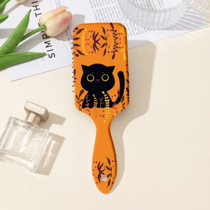 Detail of orange cushion hairbrush featuring a cute black cat and floral patterns