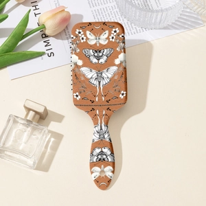 Détail d'une brosse à cheveux à motifs papillon et fleurs sur une coiffeuse