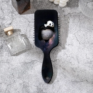 Detailed view of panda and galaxy printed hairbrush on a stylish grey background