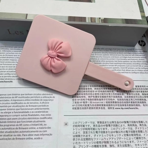 Detailed view of pink handheld mirror featuring a 3D bow decoration on the back cover