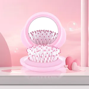 Detail of pink folding hairbrush showing integrated mirror and massage air cushion beads