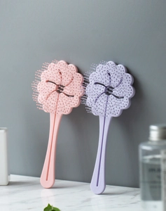 Detailed view of pink and purple floral hairbrushes on a marble surface in a bathroom