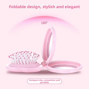 Detail of pink foldable hairbrush with compact mirror and 180 degree folding design