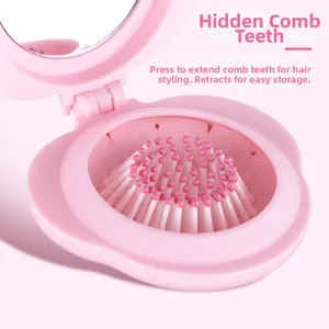 Detail of pink foldable hairbrush showing pop-up bristles and built-in mirror feature