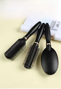Three-piece hair brush set with matte black handles and rose gold rings on beige background