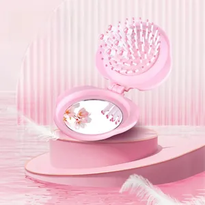 Close-up of portable folding mirror comb with pink floral design and air cushion bristles