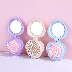 Three colorful foldable hairbrushes with makeup mirrors in purple, beige and blue
