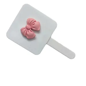 Portable cream handheld makeup mirror with pink 3D bow design and ergonomic handle