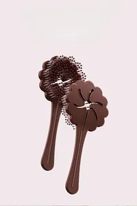 Detail of chocolate brown flower petal hair brush with hollow star pattern and flexible bristles