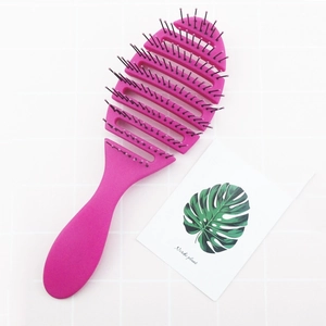 Brosse à cheveux ajourée rose avec picots de massage incurvés sur fond de carrelage blanc