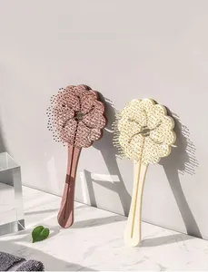 Close-up of cloud flower hairbrushes in pastel pink and cream with massage bristles