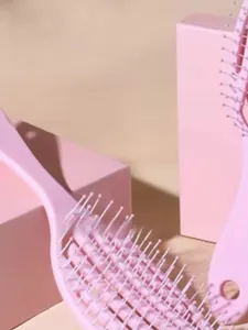 Brosses à cheveux roses ajourées pour coiffage et massage sur blocs géométriques