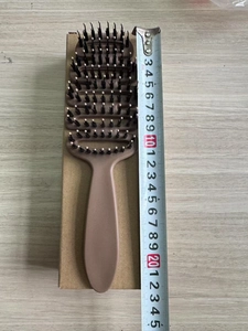 Close-up of a brown curved vent hairbrush with boar bristles and a 24.5cm ruler scale