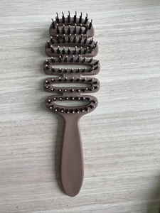 Detail view of the ventilated curved vent brush with massaged pins on wood background