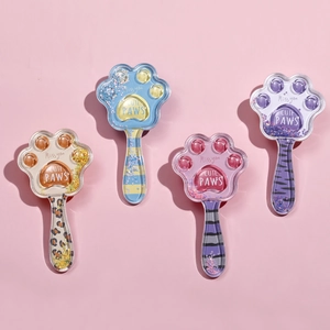 Set of four cat paw-shaped hairbrushes with colorful sequins and patterns on pink background