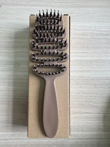 Detail of curved vented hairbrush with boar bristles and massage pins on wood background