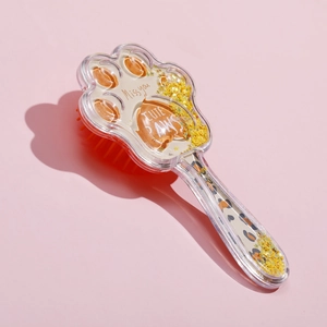 Macro view of cat paw hairbrush with leopard print, golden sequins and orange bristles