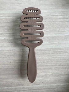 Detail of S-shaped vented hairbrush with natural bristles on a light wooden background