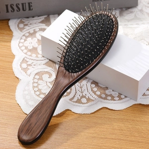 Portable air cushion hairbrush with dark wood handle and metal massage pins for styling