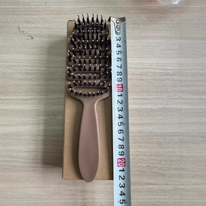 Curved anti-static boar bristle vent brush for scalp massage on light wood background