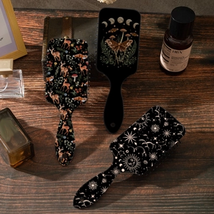 Vintage air cushion hairbrushes featuring deer and moon phase prints on a wooden surface