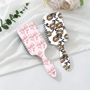 Pink bow and leopard print scalp massage air cushion hair brushes on white fabric