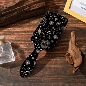 Detail shot of black air cushion hairbrush featuring celestial moon and sun patterns