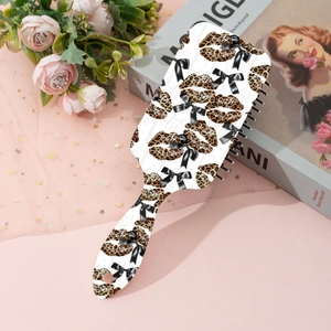 Detailed view of pink leopard print hairbrush with bow pattern on a soft floral background