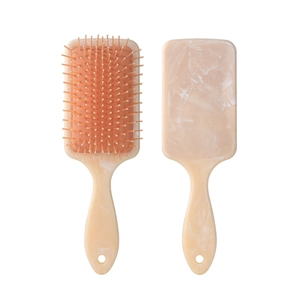 Detail view of marble patterned hairbrush with orange air cushion and massage pins