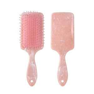 Detail of light pink marble hair brush with square cushion head and massage bristles