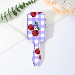 Detail of cherry plaid pattern hair brush with massage bristles on white fabric