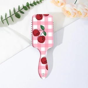 Detail of pink plaid hairbrush with cherry print and hanging hole on a floral background