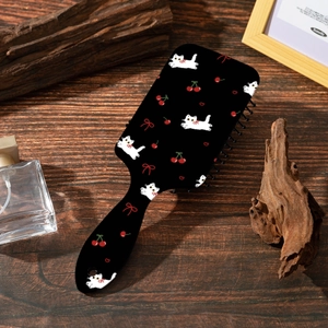 Détail de la brosse à cheveux pneumatique avec motifs chat et cerise sur bois sombre