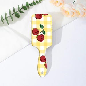 Detailed view of cherry plaid pattern hair brush on soft fabric with decorative flowers