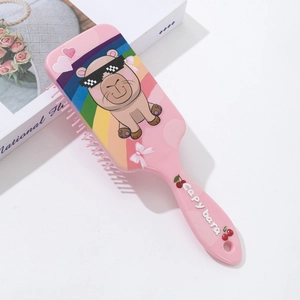 Detail of pink air cushion hairbrush featuring cute cartoon capybara and rainbow print