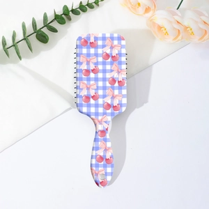 Détail de brosse à cheveux à carreaux bleus avec motifs cerises et nœuds sur tissu