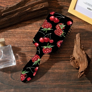 Brosse à cheveux pneumatique noire à imprimé cerise sur une surface en bois