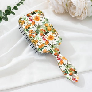 Detail of air cushion hairbrush featuring vibrant floral pattern and ergonomic handle
