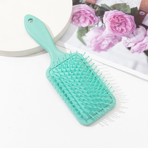 Mint green square paddle brush with ergonomic handle and cushioned bristles for scalp massage