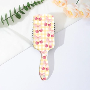Détail d'une brosse à cheveux démêlante avec motif en damier cerise et nœud rose