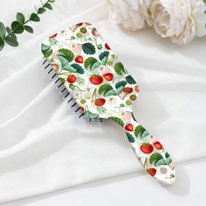 Detail of strawberry print hairbrush on white silk with floral accents for summer
