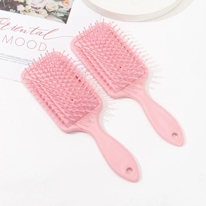 Two pink paddle hair brushes with scalp massage pins on a clean white aesthetic background