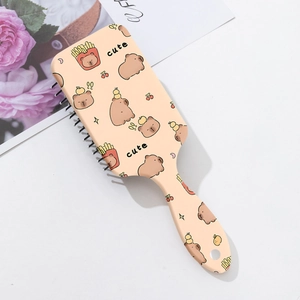 Detail of cute pink capybara cushion hairbrush with cartoon fries and cherry patterns
