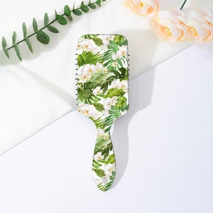 Detailed view of the hairbrush with tropical white floral and green leaf patterns