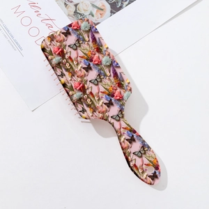 Detail of floral and butterfly print on an ergonomic ABS hairbrush with a hanging hole
