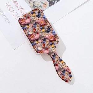Detailed view of square hairbrush back with embedded dried flowers and butterfly specimen