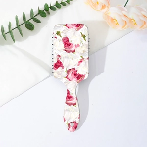 Detailed close-up of floral print hairbrush with massage bristles and hanging hole