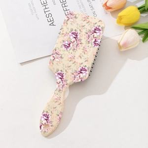 Detail of floral printed cushion hairbrush with massage bristles on a beige background