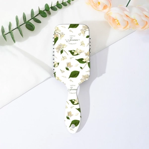 Detail of floral air cushion hairbrush with jasmine print on white silky background