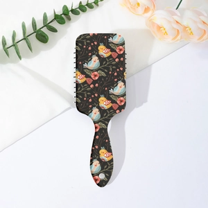 Detail view of bohemian bird and floral print on a rectangular air cushion hairbrush